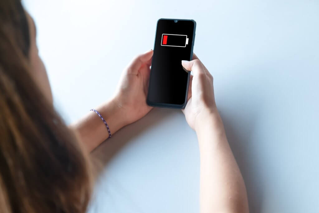 Capa do artigo "Aprendizado de máquina para reduzir consumo de energia em smartphones" que mostra uma mulher branca de cabelos longos com um smartphone nas mãos onde é possível ver que ele está com a bateria acabando.