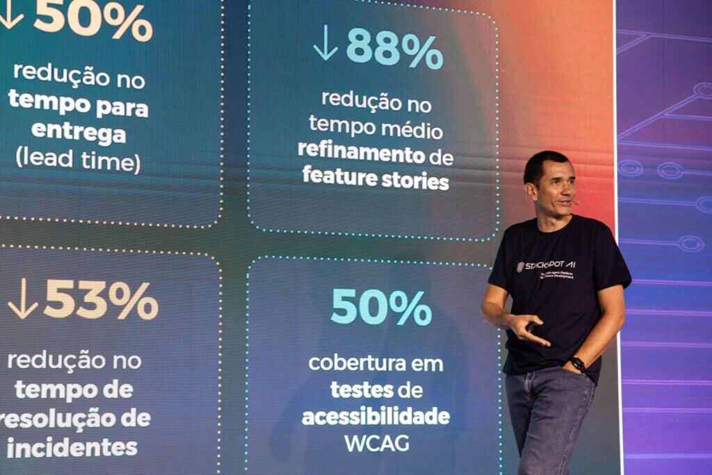 Imagem do Andre Palma, executivo da zup palestrando em cima do palco no StartSe AI Day 2024. Atrás dele, um painel com alguns números de impacto que a StackSpot pode gerar. 