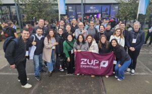 Foto do grupo da Zup Expedition em frente a entrada do World AI Summit 2025.